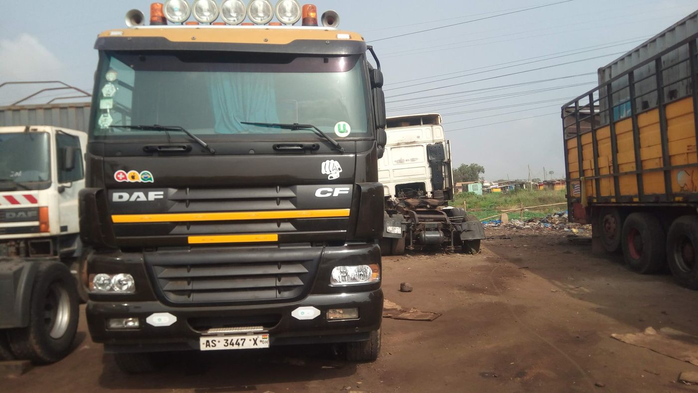 A black DAF CF tractor unit with roof lights parked in a yard